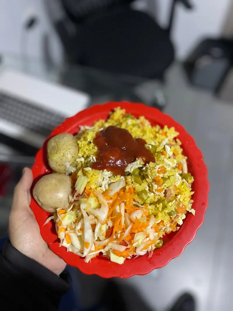 Plato de arroz con ensalada, papas y salsa, servido en la sede.