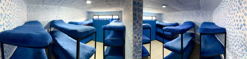 Dormitorio con camarotes de colchones azules y casilleros.